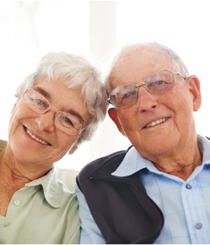Older couple facing the camera, smiling, with their heads together
