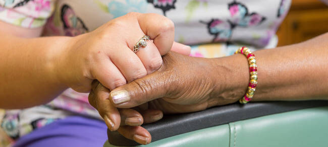 nurse and senior PACE participant hold hands