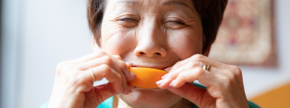 Older Asian woman eats an orange