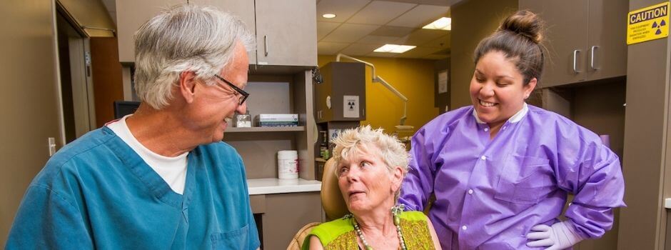 Dentist, Participant, And Dental Assistant Conversing In Dental Clinic