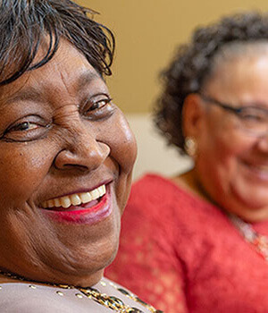 Woman smiling at camera with her friend in the background