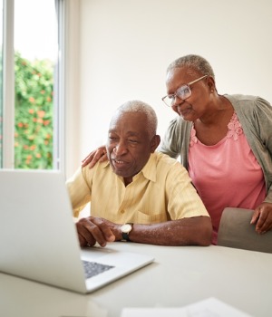 An older couple filling out a form on a laptop computer