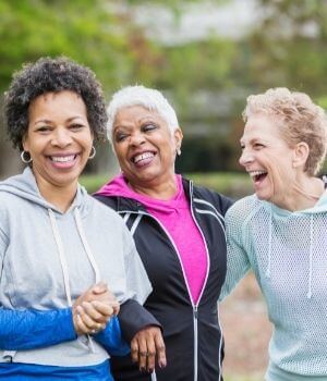Three senior women walking together and laughing.