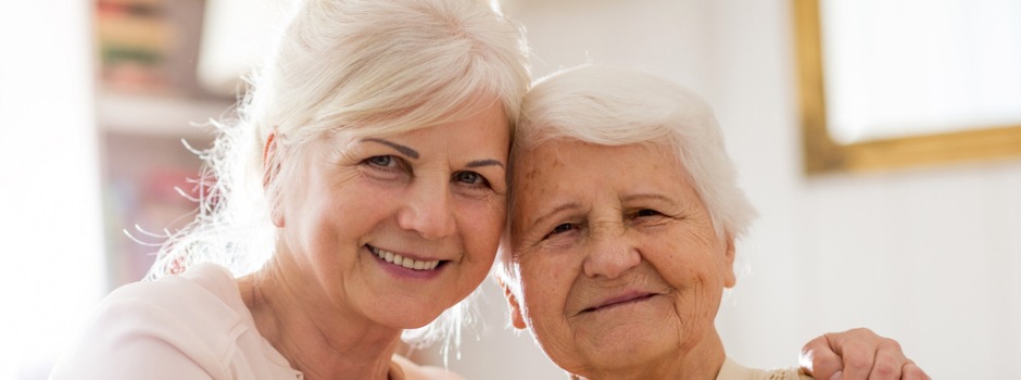 Family Caregiver And Care Recipient Hugging And Smiling
