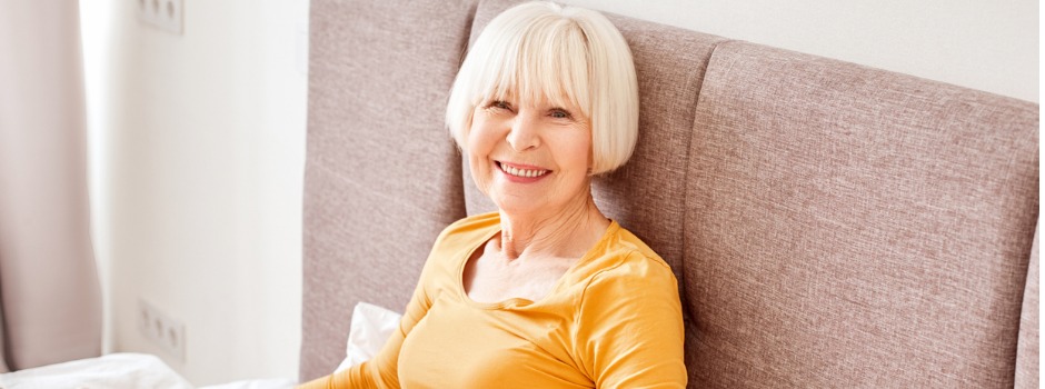 Older Woman Sitting Up In Bed Smiling